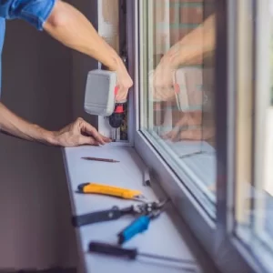 Close-up of a professional installing a new window with tools on the sill, highlighting precision and craftsmanship.