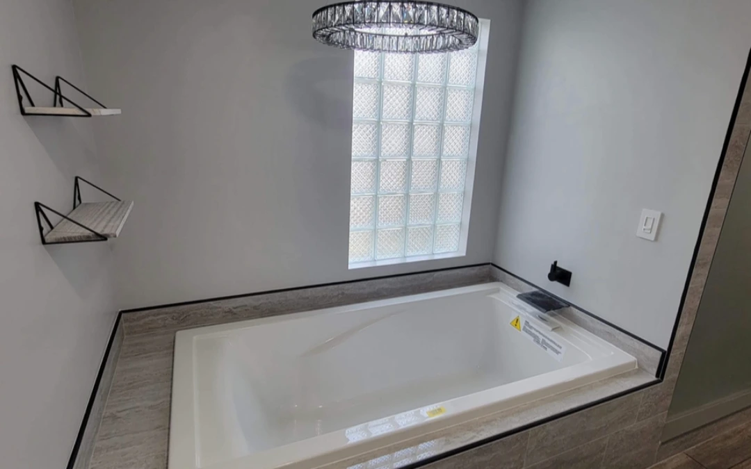 Contemporary bathtub setup with glass block window and modern fixtures