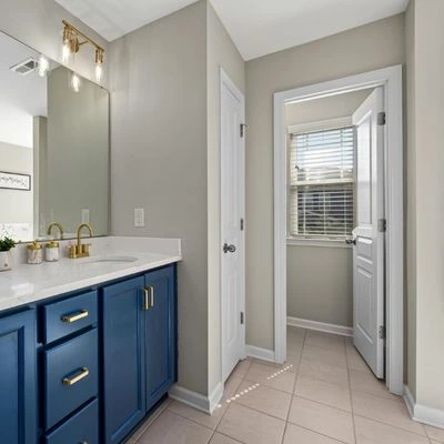 Modern bathroom remodel with blue vanity, gold hardware, and neutral walls in Michigan