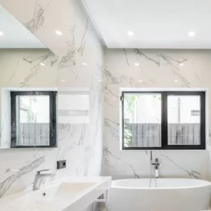 Luxury bathroom remodel with marble walls, freestanding tub, and large window in Michigan